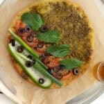 a zaatar manakoushe with sliced veggies on it