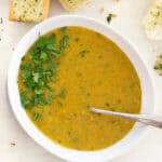 lentil carrot soup in a white bowl with a spoon