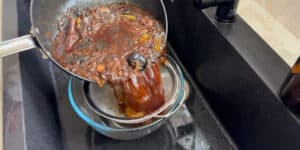 straining broth with a sieve into a glass bowl