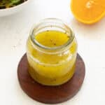 orange herb vinaigrette dressing in a glass jar, fresh ingredients for plant-based salads.