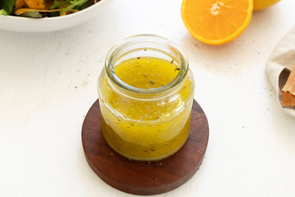 orange herb vinaigrette dressing in a glass jar, fresh ingredients for plant-based salads.