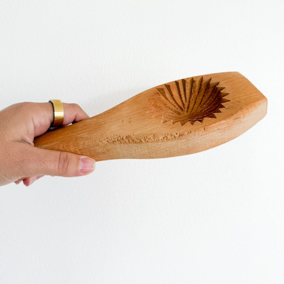 hand holding a wooden maamoul mold
