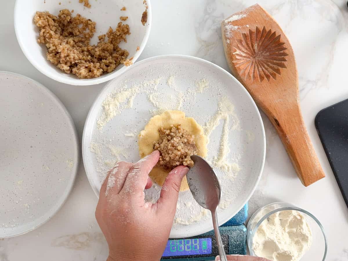 spooning walnut filling onto maamoul dough