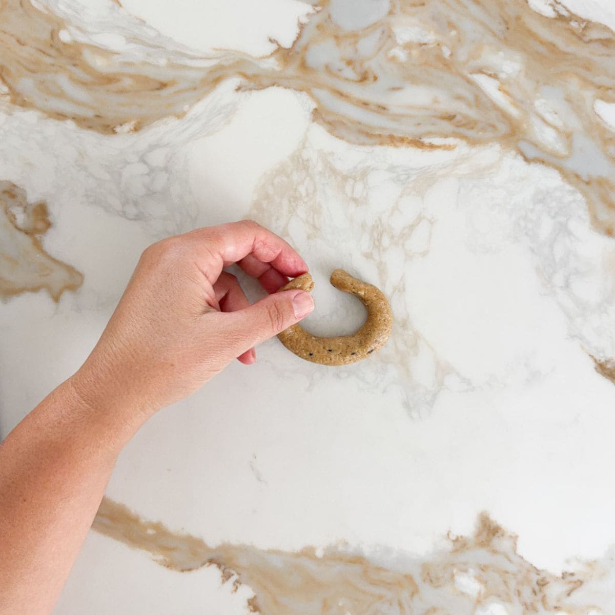 creating a anise cookie ring on a marble surface, ready for baking.