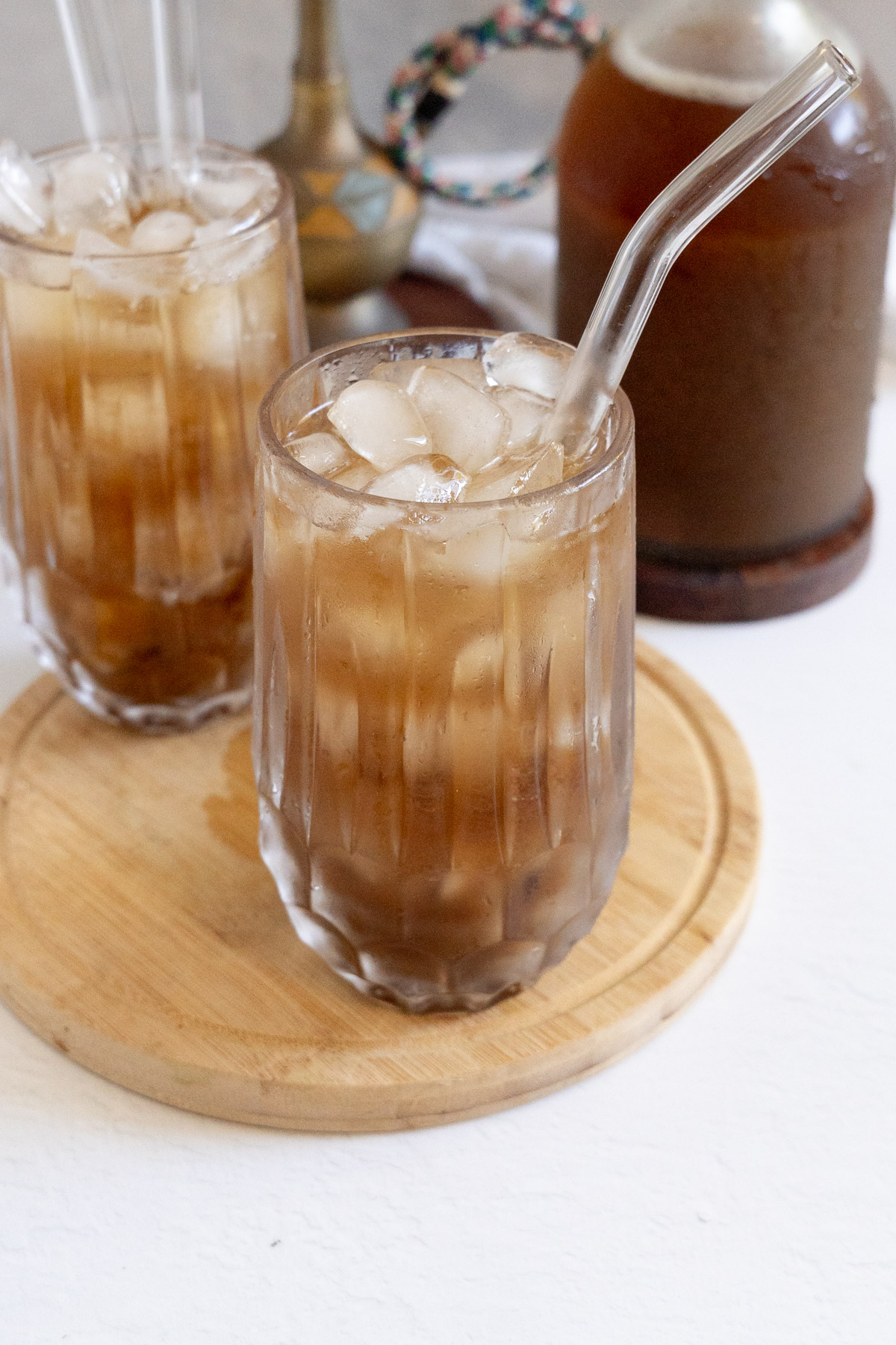 Refreshing cold tamarind juice with ice cubes in a glass, served on a wooden tray.