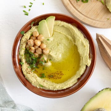 avocado hummus in a brown ceramic bowl