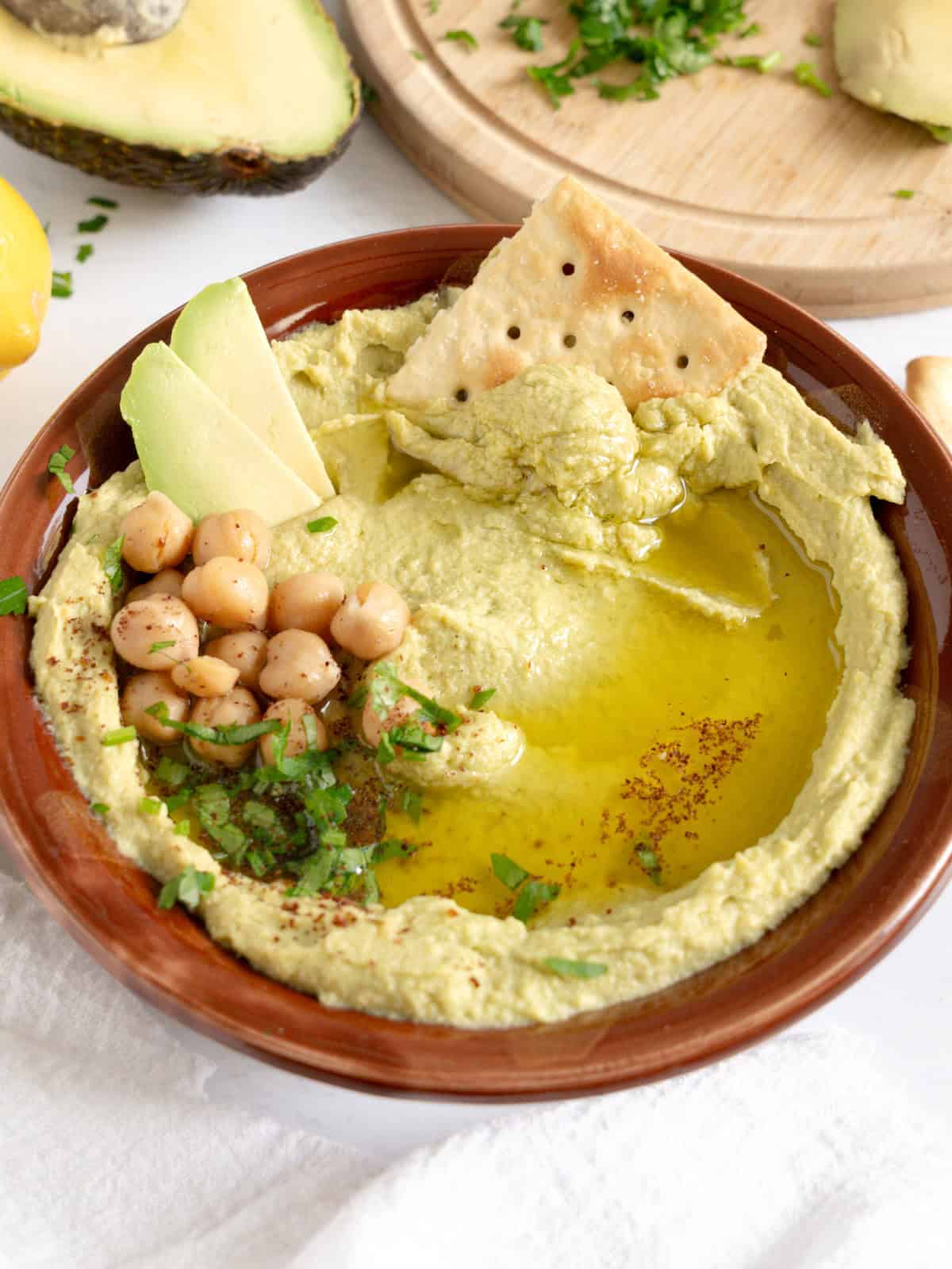 avocado hummus with crackers dipped in it