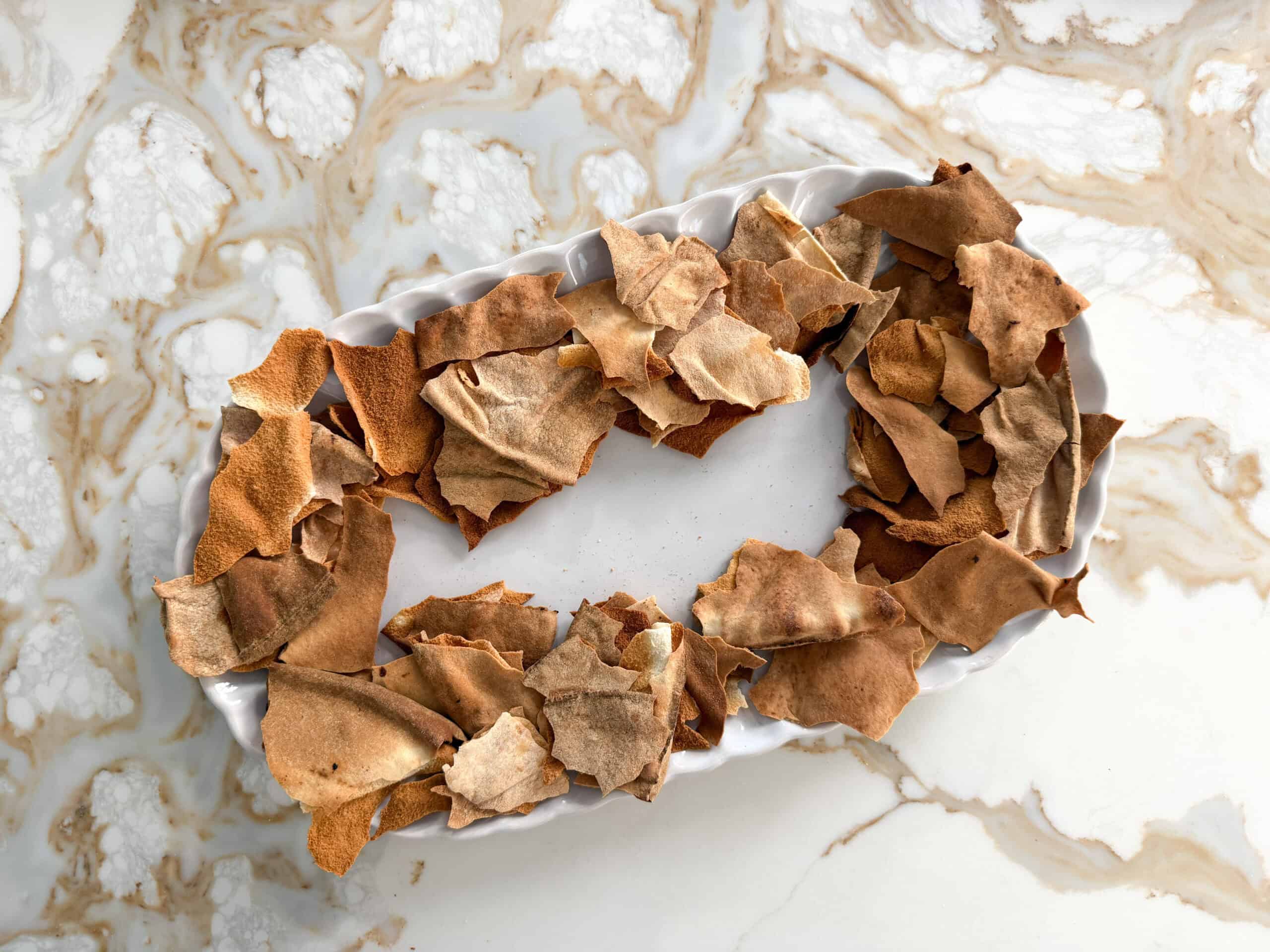 crispy broken pita bread on a white plate