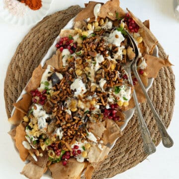eggplant fatteh in a plate with spoons in it