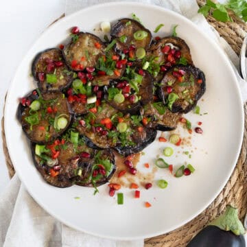 fried eggplant slices topped with dressing chopped herbs and chili