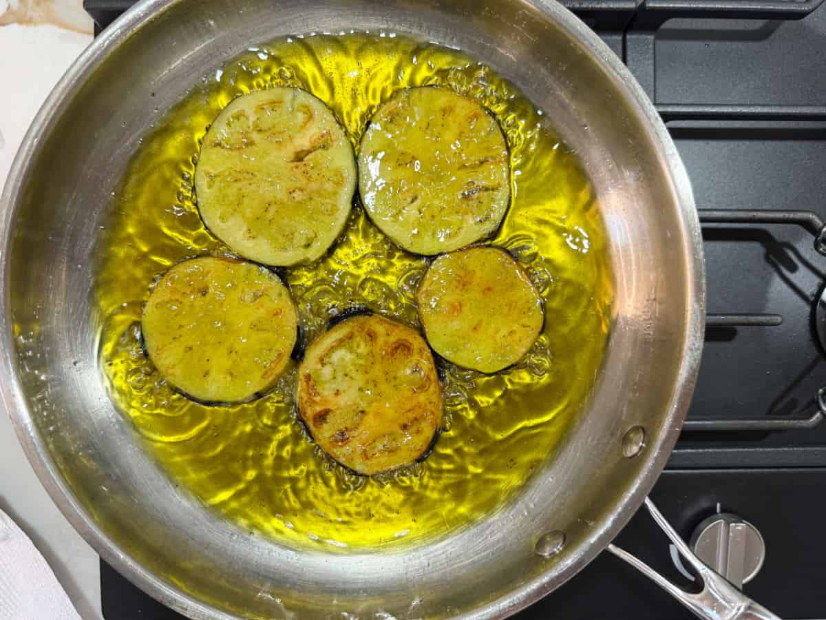 eggplant slices being fried in oil in a pan