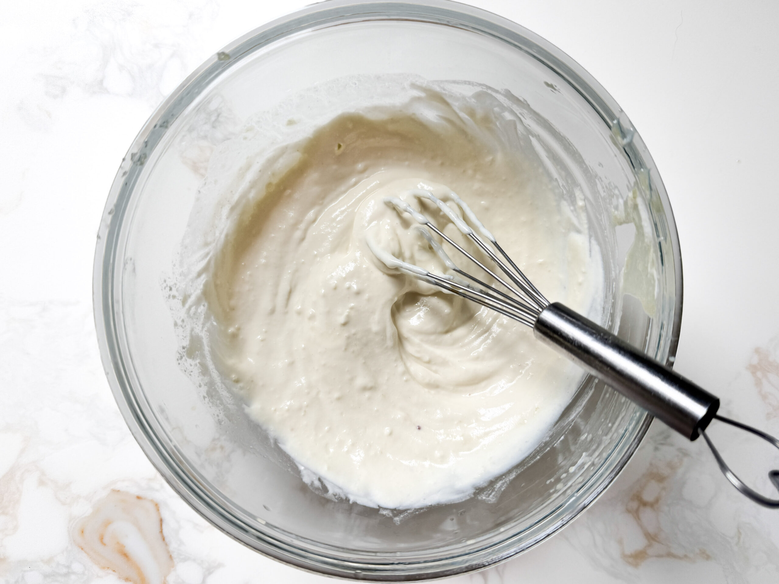 yogurt tahini dip in a bowl with a whisk