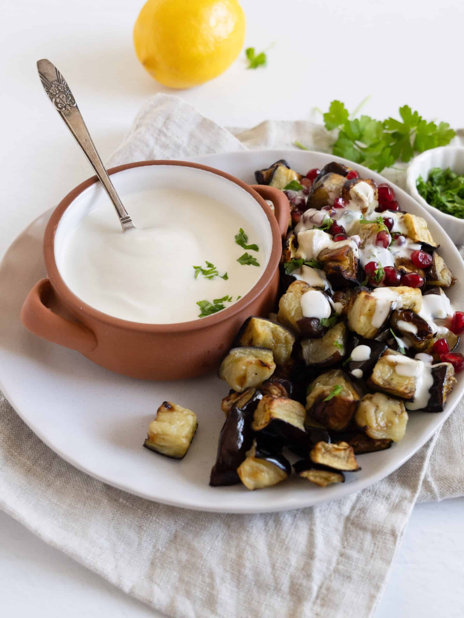 yogurt tahini sauce with fried eggplant on the side in a plate