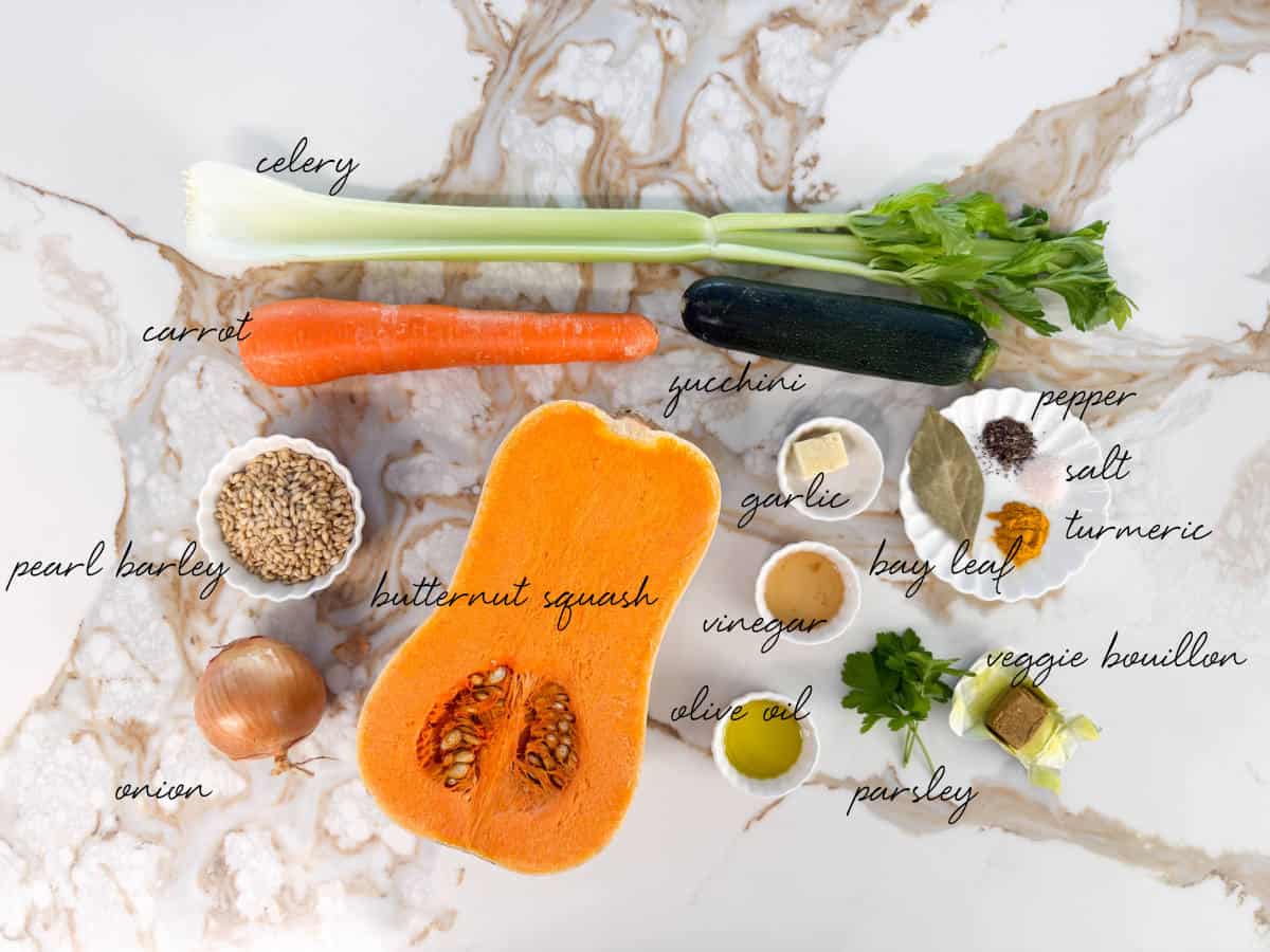 celery, carrot, zucchini, butternut squash, seasoning, spices, pearl barley, onion, bouillon cubes, vinegar and oil laid out