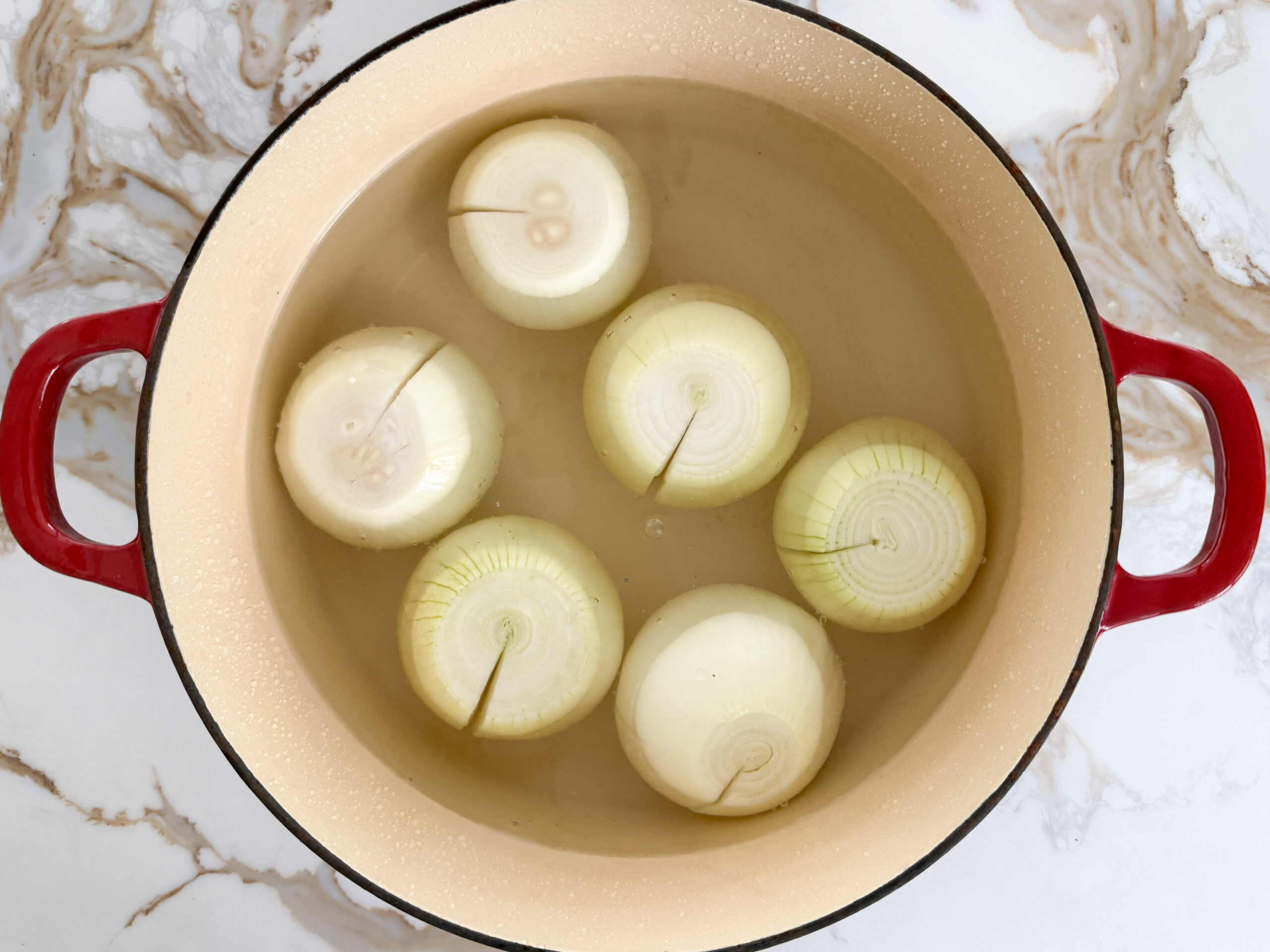 peeled whole onions with a slit in water in a pot