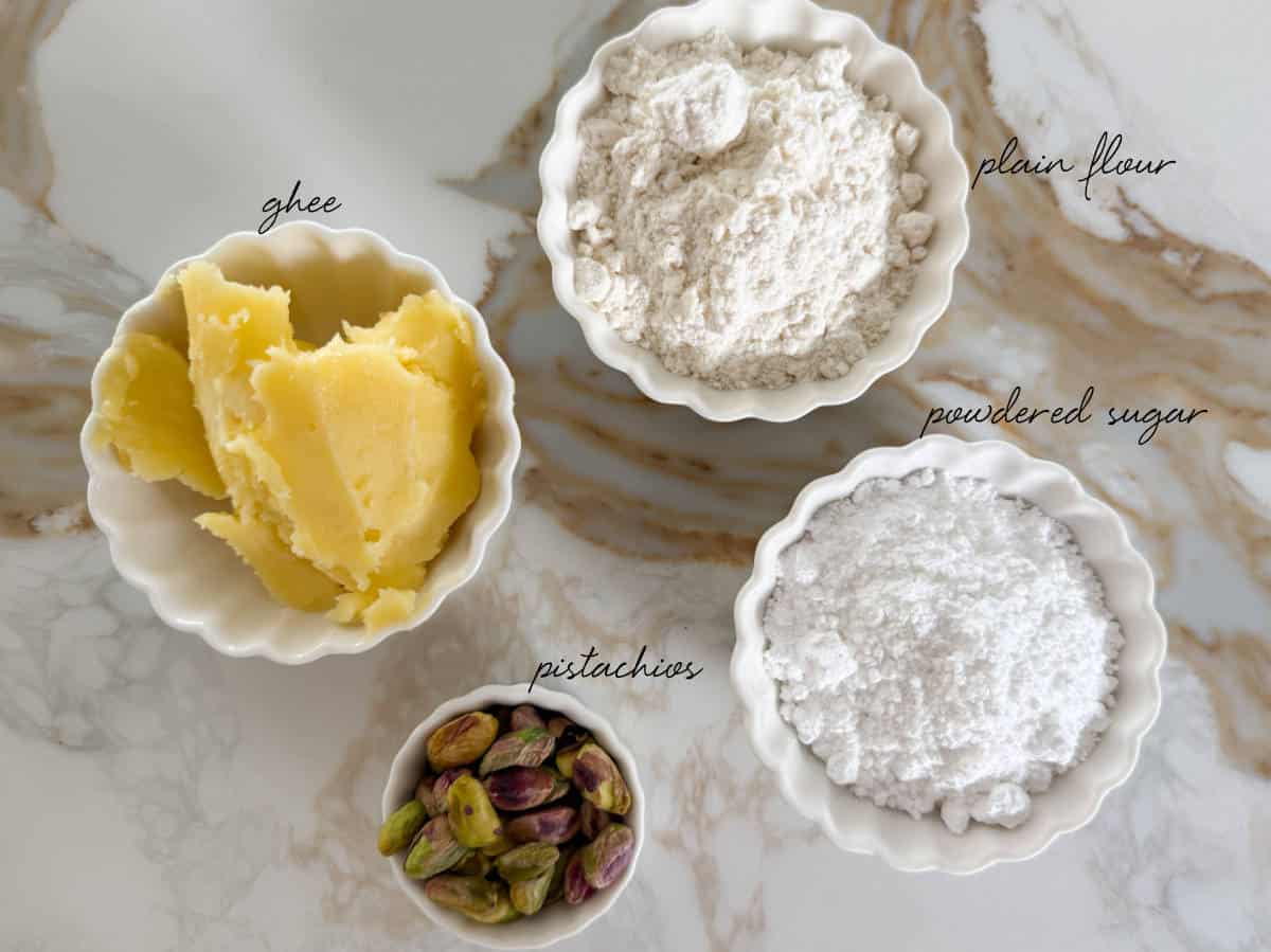 ghee, flour, powdered sugar and pistachios in bowls
