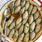 baked stuffed onions in a pan with serving utensils