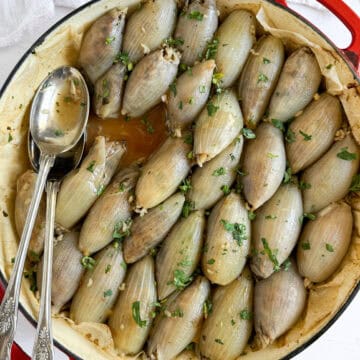 baked stuffed onions in a pan with serving utensils