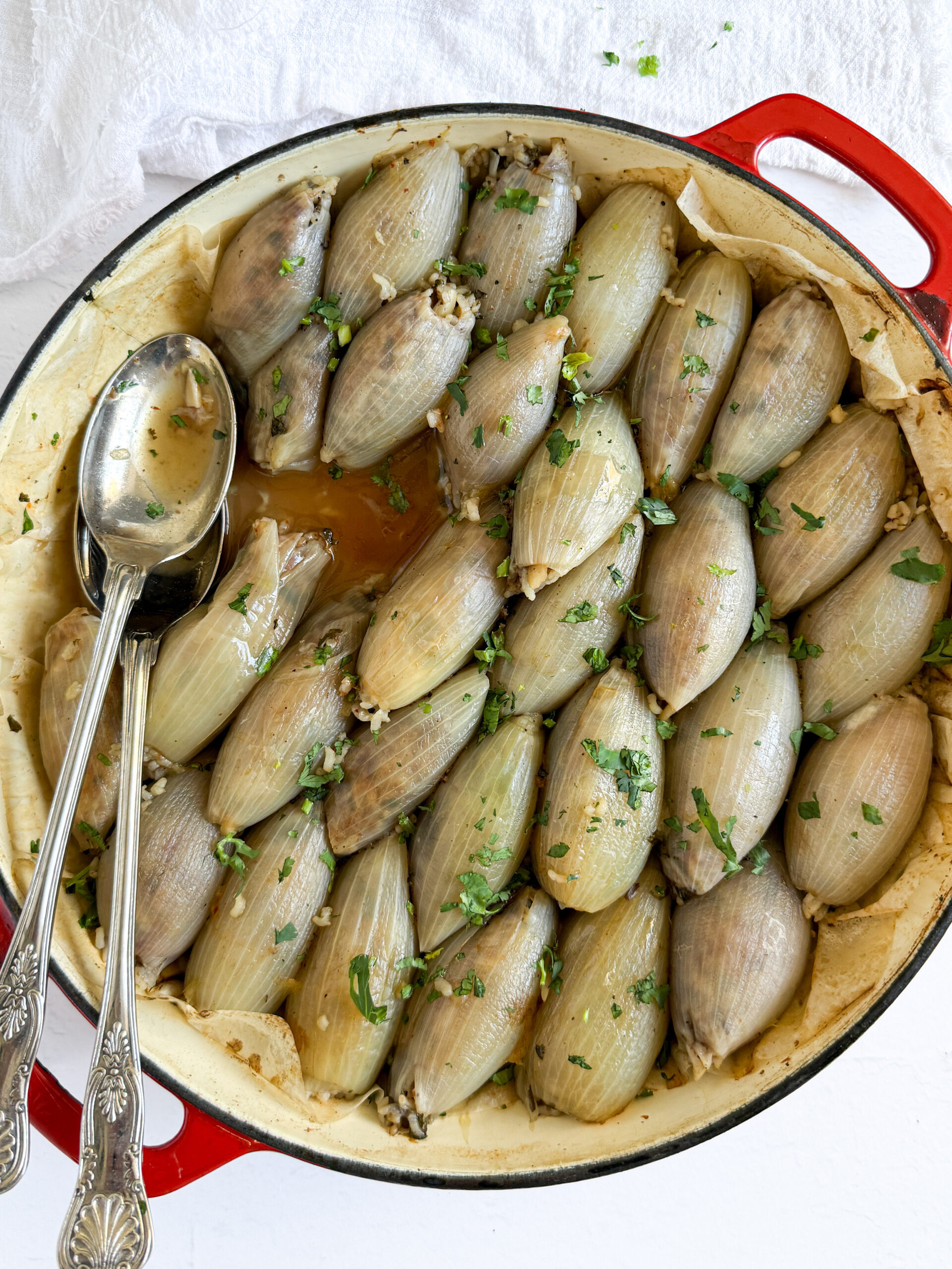 baked stuffed onions in a pan with serving utensils