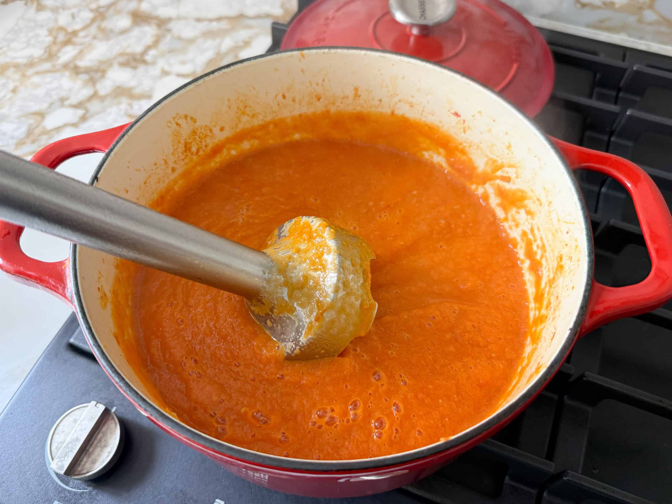 an immersion blender in a pot with pureed tomatoes