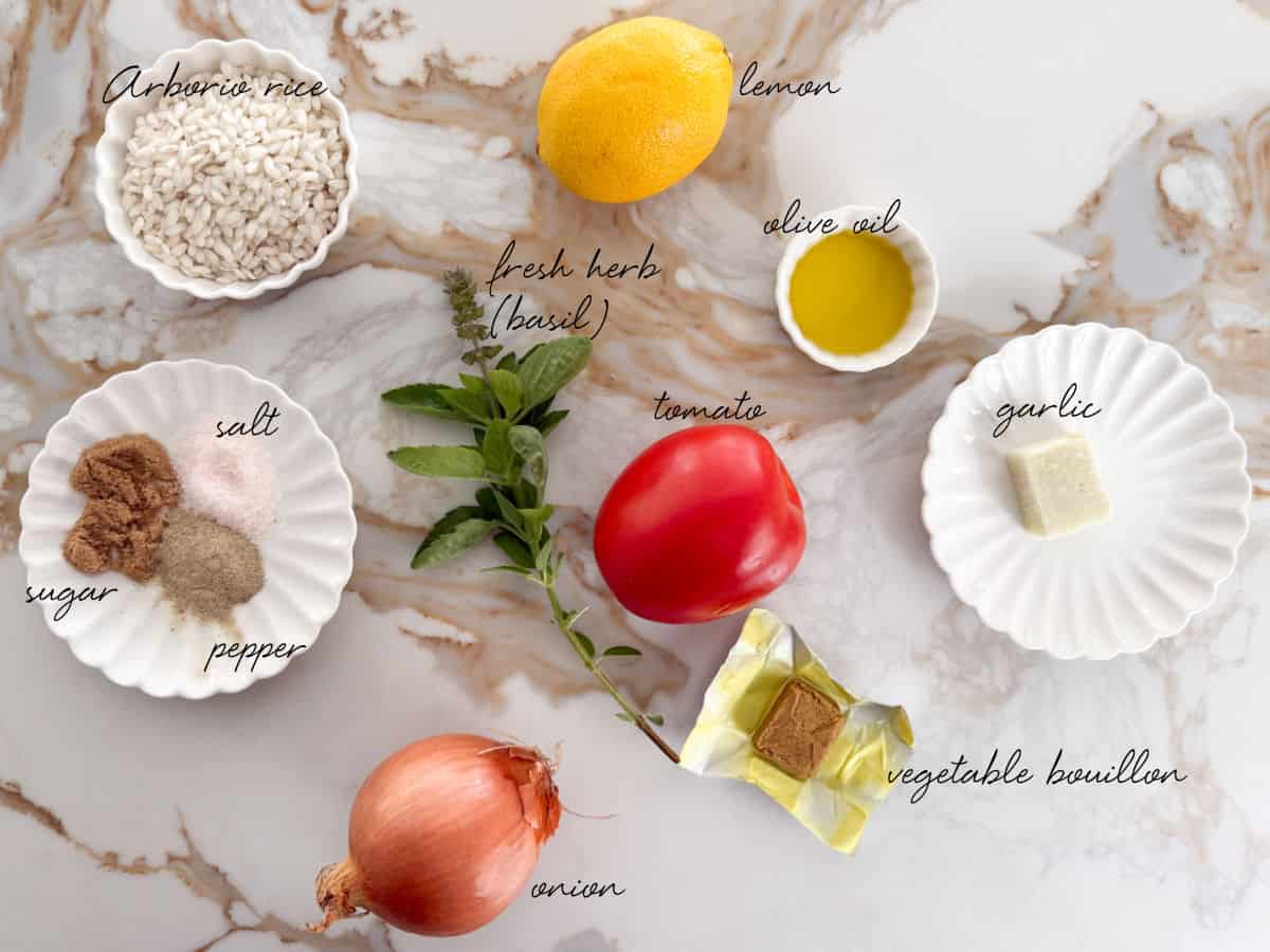 tomato, rice, lemon, oil, spices, onion, bouillon cube, basil and a cube of garlic laid out